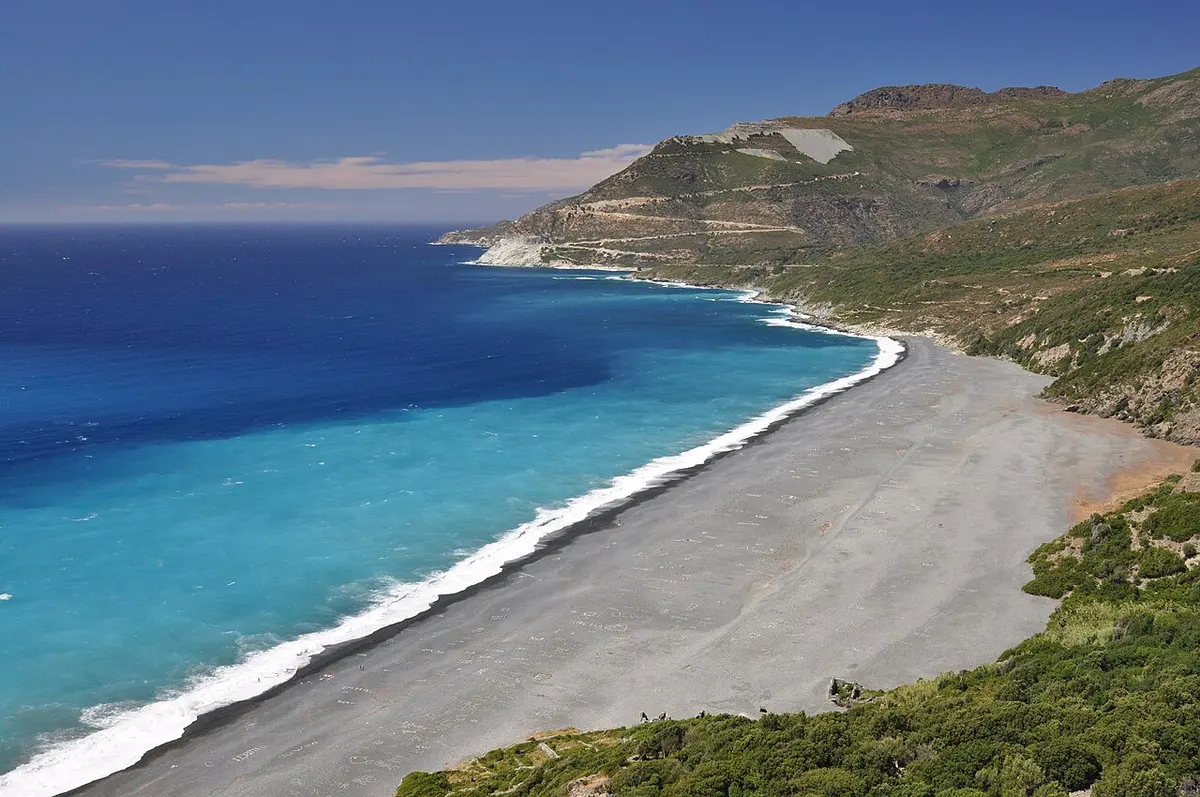 Nonza Beach, Nonza, Cap Corse, Corsica - long dark pebble beach below a cliff-top village