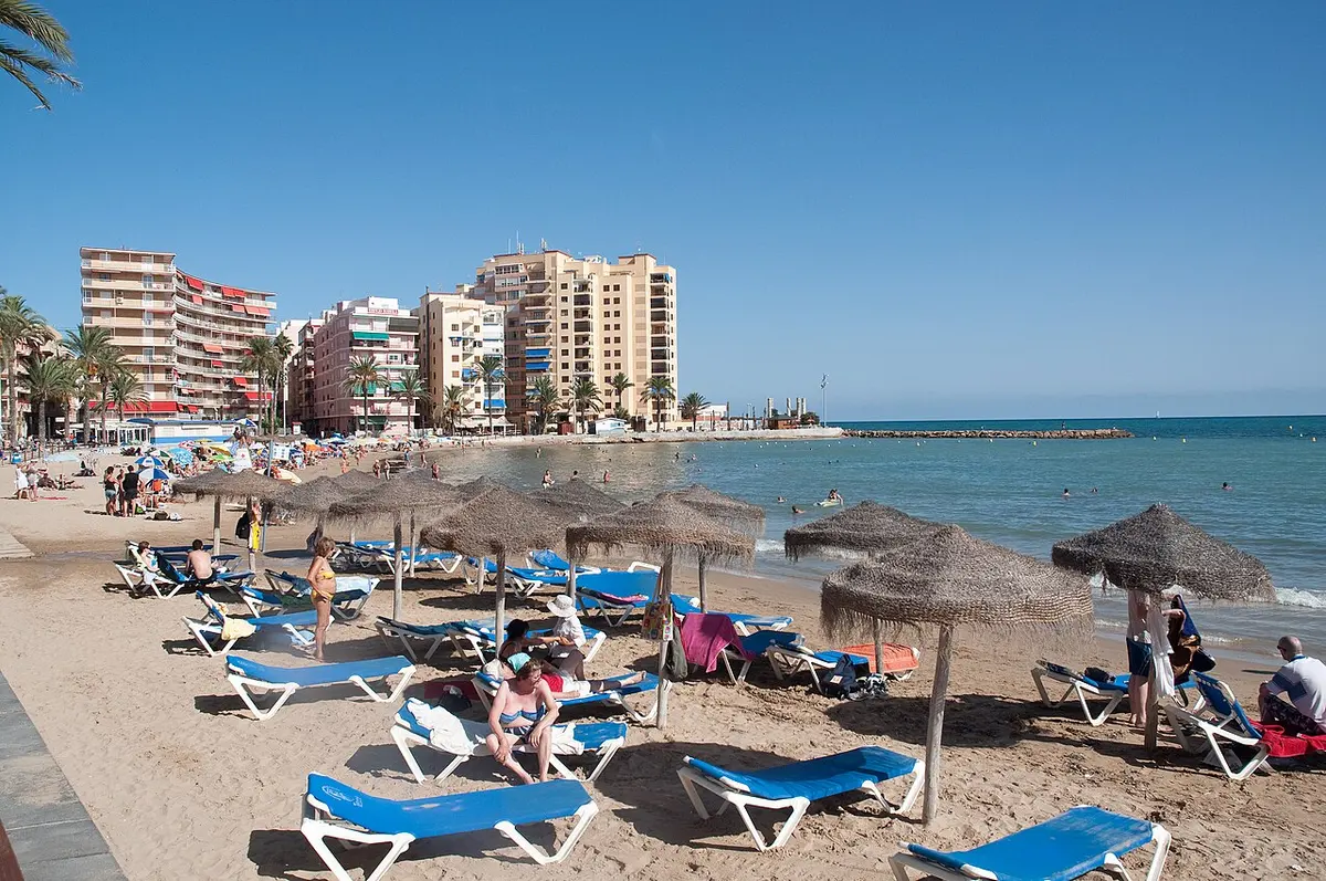 Torrevieja Beach, Torrevieja, Costa Blanca - sunbeds and thatched parasols on a warm shallow shore